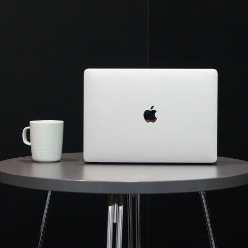 Harmaa Macbook ja valkoinen kahvimuki harmaalla pöydällä