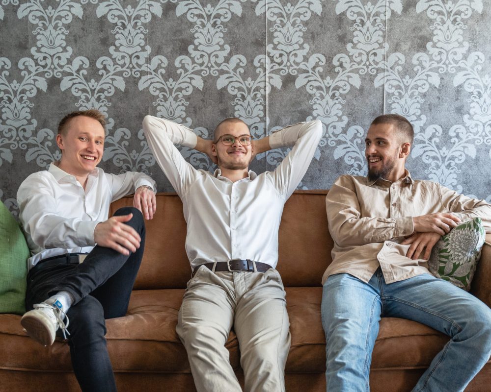 SEOverstaan yrittäjät Onni Keiskoski, Lauri Puurula ja Daniel Barkane istuvat rennosti ruskealla sohvalla.